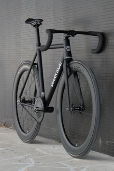 a black bike is leaning against a gray wall