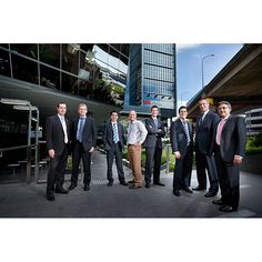 a group of men in suits and ties posing for a photo outside an office building