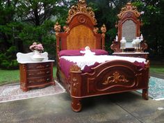 a wooden bed sitting on top of a cement floor next to a dresser and mirror