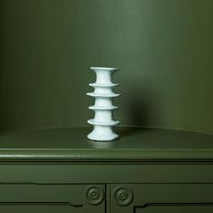 a white vase sitting on top of a green dresser