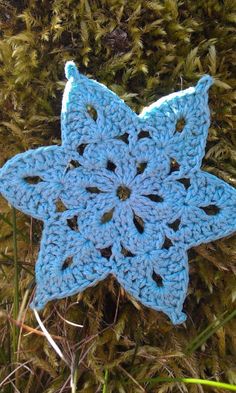 a blue crocheted star ornament sitting in the grass