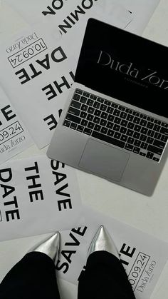 a laptop computer sitting on top of a table next to some white paper with black lettering