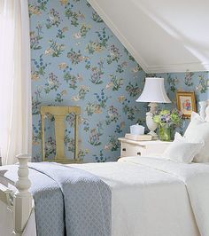 a bedroom with floral wallpaper and white bedding