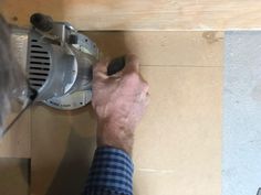 a man is using a grinder to cut up wood on the floor in front of him