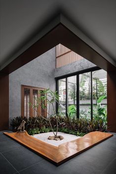 an indoor garden with plants and rocks on the ground in front of a large window