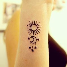 a woman's wrist with a small sun and moon tattoo on her left arm