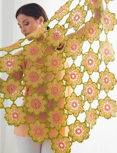 a woman is holding an intricately designed shawl