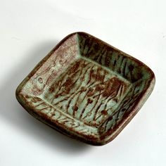 a brown and green bowl sitting on top of a white table