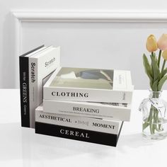 three books sitting on top of each other next to a vase with tulips