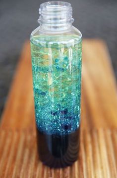 a blue and green drink sitting on top of a wooden table next to a bottle