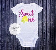 a white onesuit with the words sweet one on it and a lemon in pink