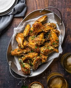 chicken wings with parsley and garlic on a plate next to small bowls of seasoning