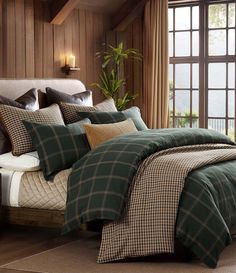 a bed with green plaid comforter and pillows in a room next to a window