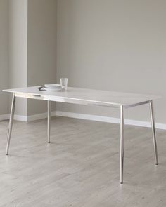 a white table sitting on top of a hard wood floor next to a gray wall