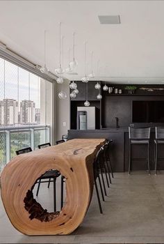 a large wooden table sitting in the middle of a living room next to a kitchen