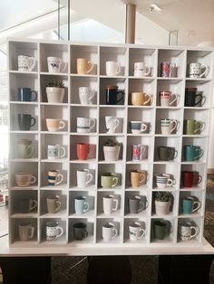 a white shelf filled with lots of coffee mugs