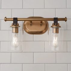 two light fixtures mounted on a white brick wall in an old - fashioned style bathroom