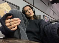 a woman wearing headphones sitting in front of a wooden table with her hand on the leg