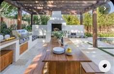 an outdoor kitchen and dining area with wood table, grilling oven, and bench