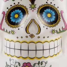 a white sugar skull with blue and yellow flowers painted on it's face is shown