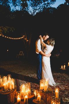 a bride and groom embrace in front of candles