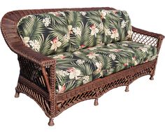 a wicker couch with tropical print fabric on it's arms and back rests against a white background