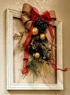 a christmas decoration hanging on the wall in front of a framed photo with red and gold ornaments