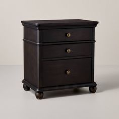 a black wooden nightstand with two drawers on wheels and one drawer open to the side