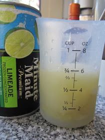 a measuring cup filled with liquid next to a can of limeade