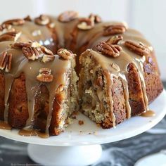 a bundt cake with pecans and icing sitting on a white platter