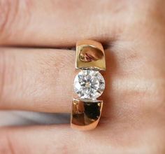 a close up of a person's hand with a diamond ring on their finger