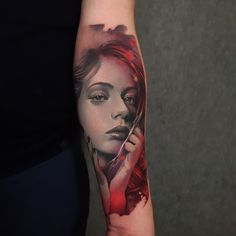 a woman's arm with a red and black tattoo design on the left forearm