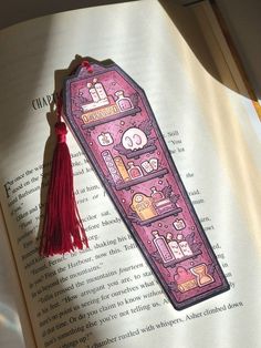 the bookmark is laying on top of an open book with a tassel hanging from it