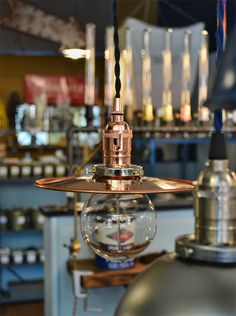 a light fixture hanging from the ceiling in a room filled with metal fixtures and other items