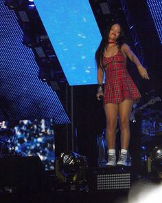 a woman standing on top of a stage wearing a red and black plaidered dress