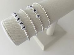 one name bracelet made with 4mm sterling silver beads bracelets are made on a durable stretch elastic cord please refer to our sizing guide before purchasing Adjustable Silver Name Bracelet With Custom Text, Adjustable White Name Bracelet With Custom Text, White Letter Beads Name Bracelet For Friendship, White Name Bracelet With Letter Beads For Friendship, White Stretch Bracelet With Letter Beads For Personalized Gift, Personalized White Stretch Bracelet With Letter Beads, Classic White Name Bracelet As Gift, Classic Personalized Beaded Bracelets For Everyday, Customizable White Bracelets For Friendship