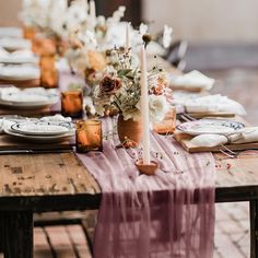 the table is set with candles, plates and napkins for an elegant dinner party