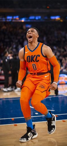 a man in an orange uniform is laughing on the court with his mouth wide open