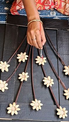 a woman is making flowers out of wire and wood beads on a table with other items