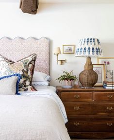 a bedroom with a bed, dresser and lamp on the side table in front of it