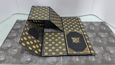 an open book with black and gold designs on the cover is sitting on a table