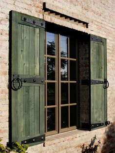 an open window with green shutters on a brick building