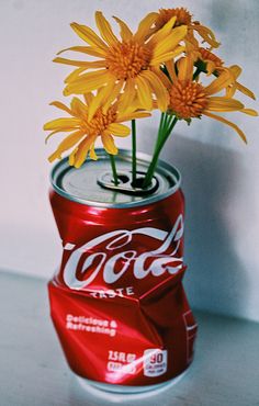 some yellow flowers are in a coke can