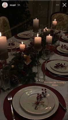 a table set for christmas dinner with candles and place settings in front of the plate