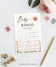 a baby shower game with pink flowers and stamps on the side, next to a gold pen