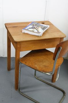 an old school desk and chair with a magazine on it