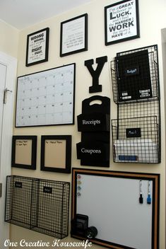 the wall is filled with many different items and framed pictures, including magnets, calendars, mailboxes, and more