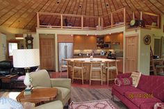 a living room filled with furniture next to a kitchen and dining room table in front of an open floor plan