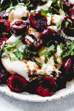 a white bowl filled with cherries and feta cheese on top of a table