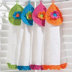 four crocheted towels hanging on a clothesline with flower decorations in the middle